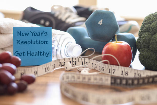 New year's resolution to get healthy in the coming year! Group of objects includes: note, fruit, tape measure,ear buds, athletic shoes, dumbbells, water bottle and towel. Concept of an individual preparing items for an exercise.